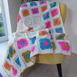 bright granny square blanket with flower squares of bright blue, bright pink and gold