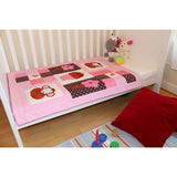 pink, white and brown patchwork quilt laying on the bottom of a cot surrounded by toys