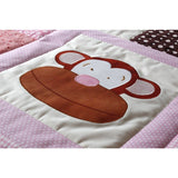 A sewn on smiling monkey face on a white patchwork square making up the squares on a patchwork quilt