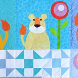 A blue fabric background with a yellow lion cub with and orange tail sat next to a round flowers of circles of red, purple and white with a green stalk and leaves